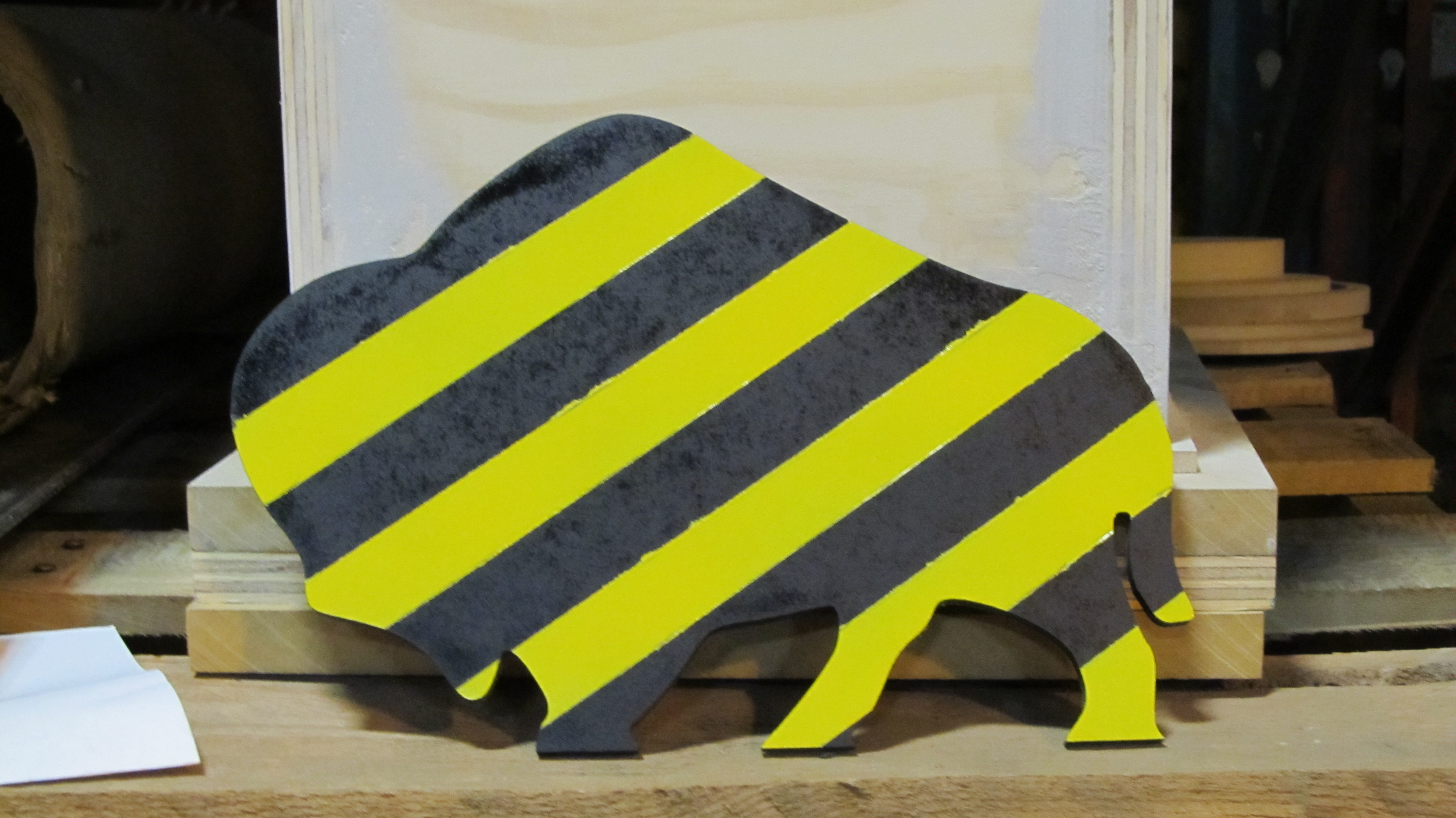 A silhouette of a buffalo, cut out of quarter-inch MDF, then painted with black and yellow caution stripes.